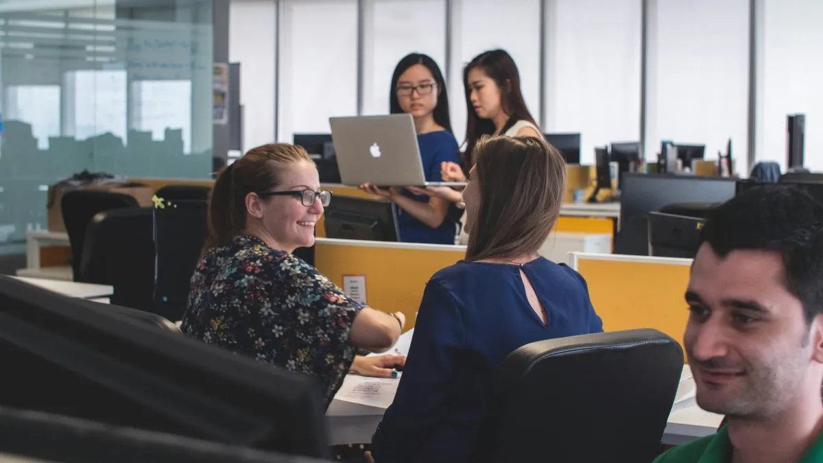 Colleagues collaborating around a laptop in a bright office